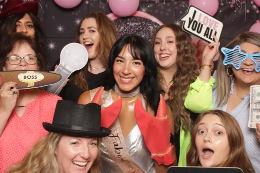 A group of guests in masquerade masks holding prop signs at a gala
