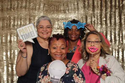 A multi generation group in feather boas holding a WON THE JACKPOT sign